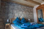 <p>Schlafzimmer mit massivem Bett, antikem Schrank und Natursteinmauer</p>